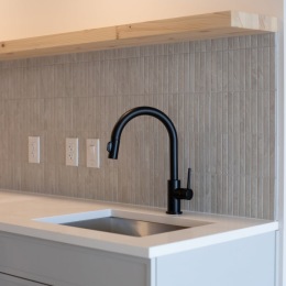 a black faucet with a tile backsplash